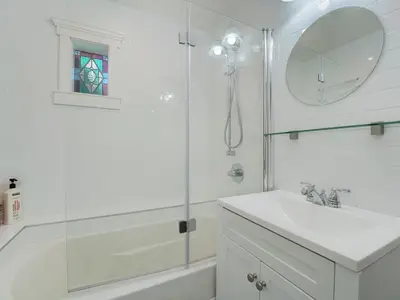 a white bathroom with a sink and a shower at Fairfield Estate Coach House - 30-Day Stay, steps from Cook Street Village by Victoria Prime! in Victoria