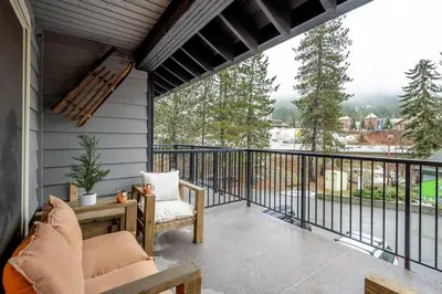 a screened in porch with a couch and chairs on a balcony at Powder & Pines Boutique Apartment in Whistler