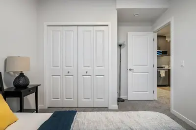 a bedroom with white doors and a bed and a lamp at Perfect Stay 2 Bedroom Basement Suite in Airdrie
