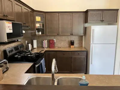 a kitchen with wooden cabinets and a white refrigerator at 4br Crew House - Big, Bright, Modern, Fully Stocked in Grande Prairie