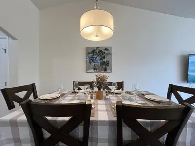 a dining room table with chairs and a light fixture at 4br Crew House - Big, Bright, Modern, Fully Stocked in Grande Prairie