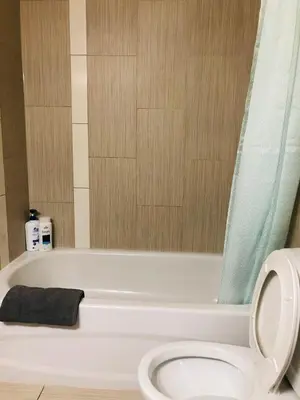 a bathroom with a white tub and a toilet at 5th Floor 1 Bedroom Condo with Parking in Calgary