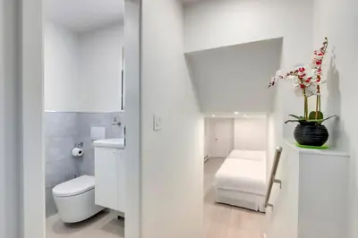 a white bathroom with a toilet and a sink at Modern King-Size Guest Suite in Burnaby