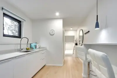 a white kitchen with a sink and a mirror at Modern King-Size Guest Suite in Burnaby