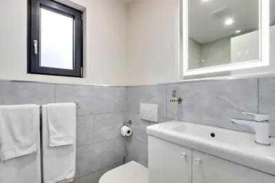 a bathroom with a sink and a toilet and a window at Modern King-Size Guest Suite in Burnaby