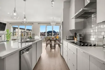 a kitchen with white counters and a table with chairs at 3 Bedroom Sage House with AC, Driveway Parking, King Bed & More in Calgary