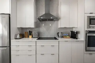 a kitchen with white cabinets and a stove top oven at 3 Bedroom Sage House with AC, Driveway Parking, King Bed & More in Calgary