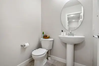 a white bathroom with a toilet and a mirror at 3 Bedroom Sage House with AC, Driveway Parking, King Bed & More in Calgary