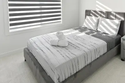 a bedroom with a bed with a white blanket and a window at Luxury 3 Bdrm 3 Bath townhome in Chestermere in Chestermere