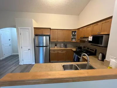 a kitchen with wooden cabinets and a stainless steel refrigerator at Park View Paradise - Big, Bright, Modern, Fully Stocked in Grande Prairie