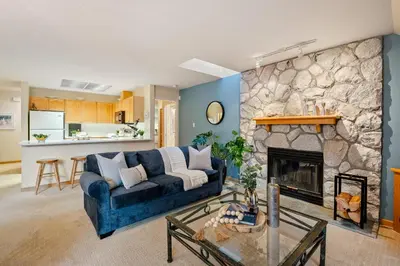 a living room with a blue couch and a stone fireplace at 31 GlenEagle in Whistler