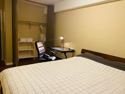 a bedroom with a bed and a chair and a lamp at 5th Floor Cozy 1 Bedroom Condo with Parking in Calgary