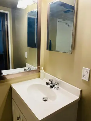 a bathroom with a white sink and a mirror at 5th Floor Cozy 1 Bedroom Condo with Parking in Calgary