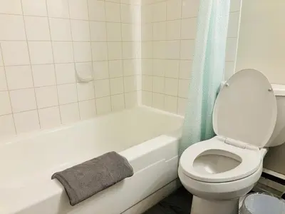 a bathroom with a toilet and a bath tub with a towel at Cozy 1 Bedroom Condo with Parking in Calgary