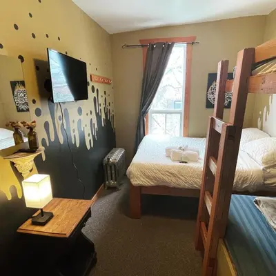 a bedroom with two bunk beds and a television at Mountain Shadow Hostel in Rossland