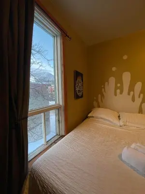 a bedroom with a bed and a large window at Mountain Shadow Hostel in Rossland