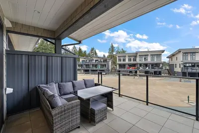 a patio with a couch and a table on a balcony at The Beach House at Saratoga Modern Beach Oasis in Oyster Bay