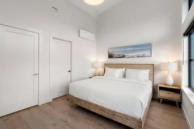 a white bedroom with a bed and a window at The Beach House at Saratoga Modern Beach Oasis in Oyster Bay
