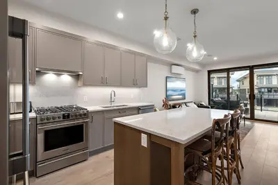 a kitchen with stainless steel appliances and a table with chairs at The Beach House at Saratoga Modern Beach Oasis in Oyster Bay