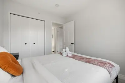 a white bedroom with a bed with a teddy bear on it at Spacious 4-Bedroom Retreat Near Bow River with Foosball, Dart Board, Movie Room in Calgary