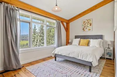 a bedroom with a bed and a large window at Rolling Hills Retreat - Family Friendly in Millarville