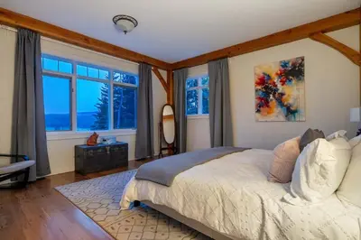a bedroom with a large bed and windows at Rolling Hills Retreat - Family Friendly in Millarville