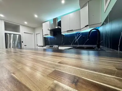 an empty kitchen with a wooden floor and white cabinets at Charming & Compact Retreat in St. Albert