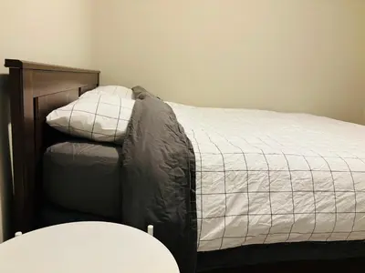 a bed with a wooden headboard and white sheets at Walkout Basement Suite with Free Street Parking in Calgary