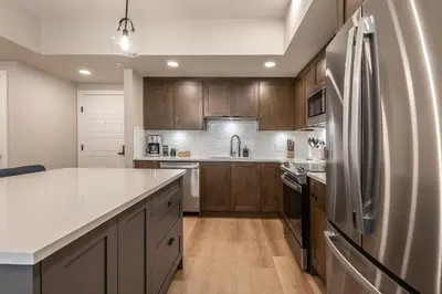 a kitchen with wooden cabinets and a stainless steel refrigerator at La Sombra at Sparrowhawk Lodge Brand New 2Bd in Dead Man's Flats