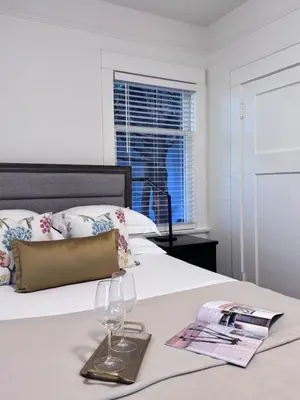 a bed with two wine glasses and a magazine on it at Deluxe Queen Room Private Ensuite Vancouver West in Vancouver