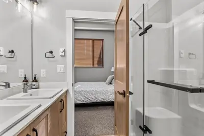 a bathroom with a sink and a shower and a bed at Powder Heights #15 home in Sun Peaks
