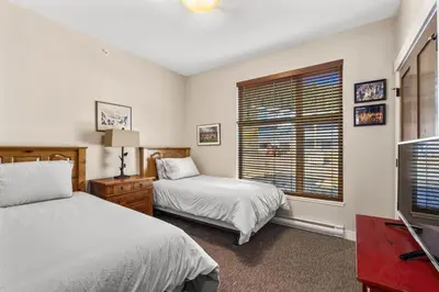 a bedroom with two beds and a tv and a window at Powder Heights #15 home in Sun Peaks