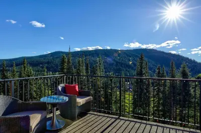 a balcony with chairs and a table and mountains at Powder Heights #15 home in Sun Peaks
