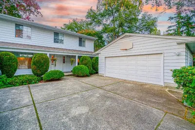 a white house with a garage and a driveway at Garden Hotel 3-bedroom house for whole book in Richmond