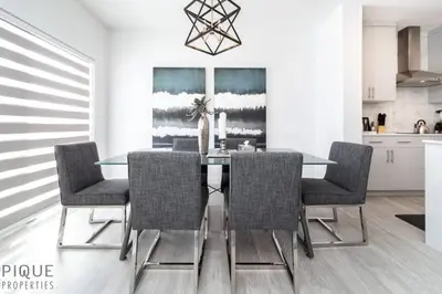 a dining room with a glass table and chairs at Modern Executive Home-Sleeps12-KingBeds-FullHouse in Edmonton