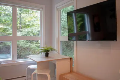 a room with a table and a tv and two windows at 1BR in Gondola Village, Near Gondola, Free Parking, Updated Unit, Incredible Location in Whistler