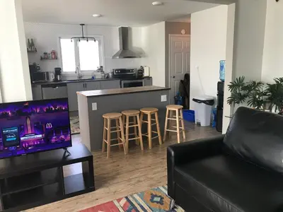 a living room with a couch and a kitchen at Northern Rainbow Upper Level Suite in House in Yellowknife