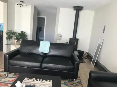 a black leather couch in a living room with a stove at Northern Rainbow Upper Level Suite in House in Yellowknife