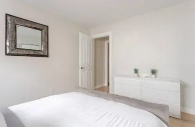 a white bedroom with a bed and a mirror at The Oxford Signature Luxury Entire Family Suite in Coquitlam