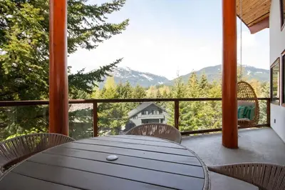 a table and chairs on a balcony with a view at White Gold Chalet - Spacious Family-Friendly Chalet, Hot Tub, Mountain Views, Log Fireplace in Whistler