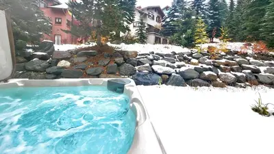 a jacuzzi tub in a yard with rocks at Timberline Village #12 home in Sun Peaks