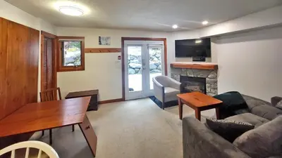 a living room with a couch and a table and a fireplace at Timberline Village #12 home in Sun Peaks