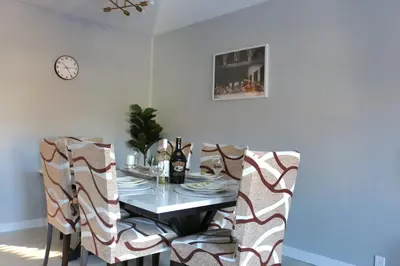 a dining room table with chairs and a clock on the wall at The WEM House in Edmonton