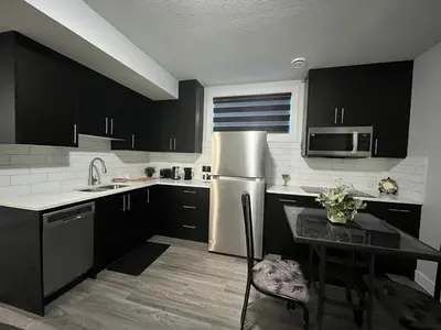 a kitchen with black cabinets and a stainless steel refrigerator at Arriva Homestay in Calgary
