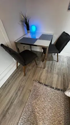 a dining room table with two black chairs and a rug at ALL NEW 2BR Loft in Chilliwack