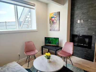 a living room with two pink chairs and a tv at Luxury Cozy Basement in Leduc