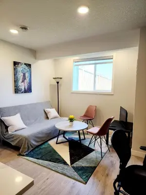 a living room with a couch and a table and chairs at Luxury Cozy Basement in Leduc