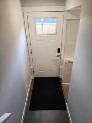 a hallway with a white door and a black rug at Luxury Cozy Basement in Leduc