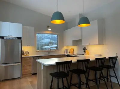 a kitchen with three bar stools and a counter top at 4595 Alpine Way by StayIn in Fernie