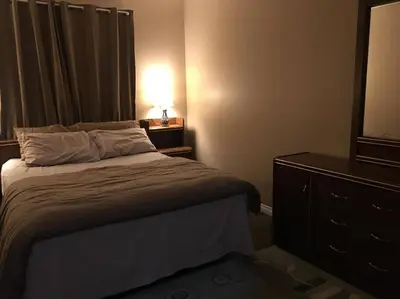 a bedroom with a bed and a dresser and a lamp at Renovated 4 bedrooms 20 sleeps Shopping Center in Edmonton